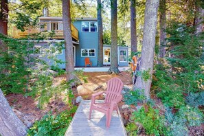 A cabin with a deck, surrounded by trees.