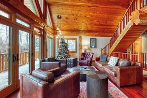 Ein geräumiges Wohnzimmer mit Ledersofas, einem Couchtisch und einem Weihnachtsbaum.