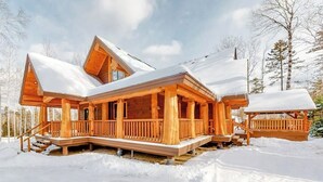Eine Holzhütte mit Veranda und überdachter Terrasse, umgeben von Schnee.