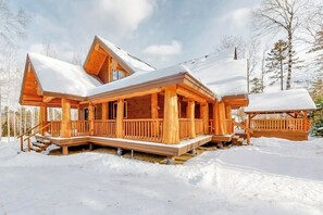 Eine Holzhütte mit Veranda und überdachter Terrasse, umgeben von Schnee.