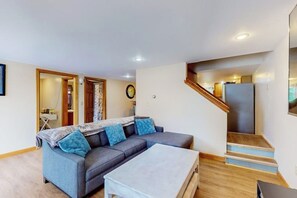 Ein Wohnzimmer mit einer Couch, einem Couchtisch und einer Treppe, die in einen anderen Raum führt.