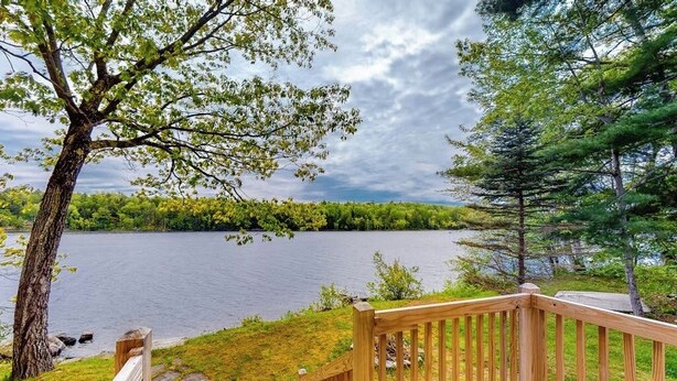 A wooden deck with a view of a lake and surrounding trees.
