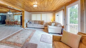 A wooden-paneled room with a sofa, a dining table with chairs, and a kitchen area.