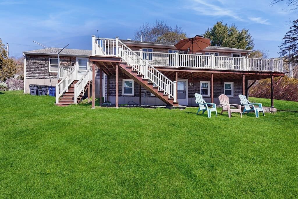 A two-story house with a covered porch, a staircase, and outdoor seating.