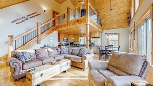 Un amplio salón con una escalera de madera, un sofá modular grande y una zona de comedor.