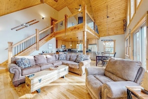 A spacious living area with a wooden staircase, a large sectional sofa, and a dining area. - The Escape at ThunderSnow Sunday River lodge with Stunning Views to Wake Up to (Bethel)