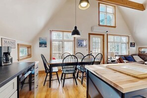 A kitchen with a dining table, chairs, a coffee machine, and a large window. - Dog-friendly Woodland home near ski resort with firepit (Greenwood)