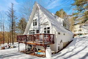 Una casa bianca con una veranda in legno e un cortile innevato.