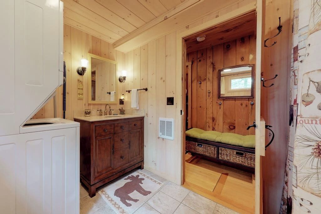 Un intérieur en bois comprenant une salle de bain, un lit avec un matelas vert et un miroir fixé au mur.