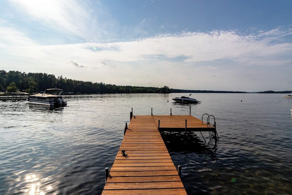 A wooden dock extending into calm water with boats docked nearby.