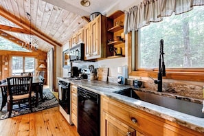 Ein Holzblockhaus-Interieur mit Küche, Essbereich und Blick auf den Wald.