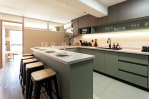 Eine moderne Küche mit Barbereich, Barhocker, einer Spüle und einer Arbeitsplatte mit Glaswaren.