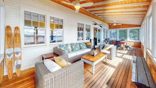 A covered porch with wicker furniture, a ceiling fan, and large windows. - Lakefront home with private dock, kayaks, firepit, grill, & sunroom (Monmouth)