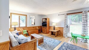Un salon confortable avec un canapé, un téléviseur, une petite table et une fenêtre avec des rideaux.