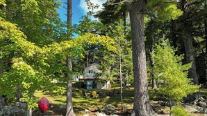 Une maison entourée d’arbres, dotée d’une terrasse visible et d’un espace salon extérieur.
