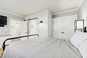 Ein Schlafzimmer mit Bett, weißen Wänden, einer Tür und einer Lampe.