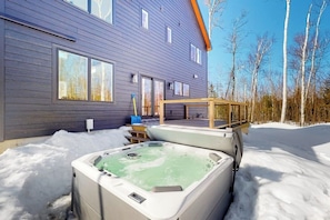 Ein modernes, zweistöckiges Haus mit Whirlpool inmitten Schnee.