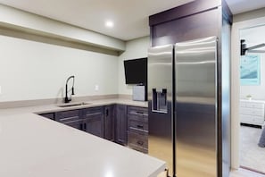 Eine moderne Küche mit dunklen Schränken, einem Edelstahl-Kühlschrank und einem integrierten Wasserspender.