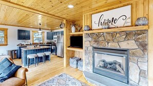 A wooden interior with a stone fireplace, a bar area, and a kitchen. - Dog-friendly Sunday River retreat with large yard, grill, washer/dryer (Bethel)