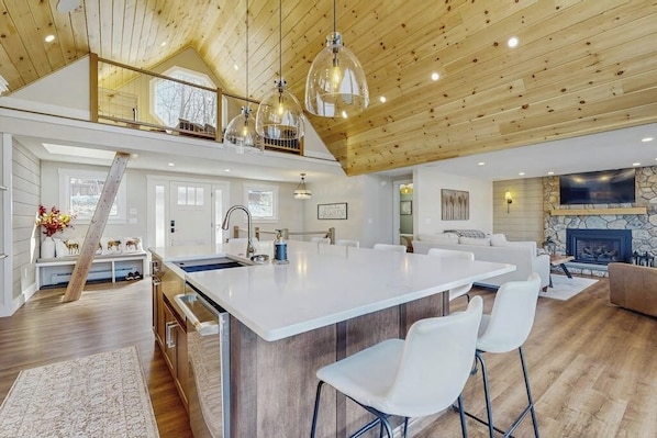 Cucina spaziosa con isola grande, soffitto in legno e luci a sospensione.