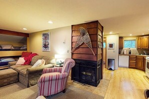 Ein gemütliches Wohnzimmer mit Kamin, einer Couch, einem gestreiften Sessel und einem Etagenbett.