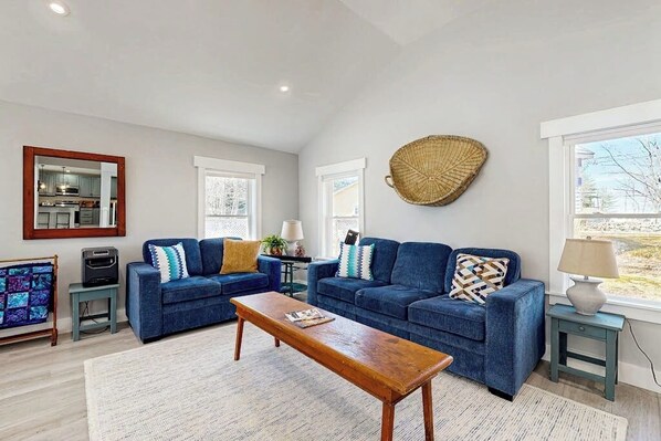A living room with two sofas, a coffee table, and a large woven wall hanging.