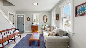 A living room with a bench, a sofa, a coffee table, a dresser, and a door.
