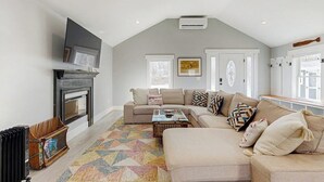 A living room with a fireplace, a sectional sofa, a coffee table, and a television.