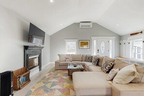 Ein Wohnzimmer mit Kamin, einem Ecksofa, einem Couchtisch und einem Fernseher.