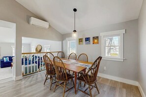 Un comedor con una mesa y sillas de madera, una lámpara colgante y un ventanal con vistas.