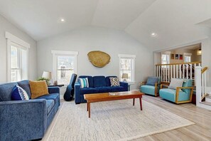 Ein geräumiges Wohnzimmer mit einem blauen Sofa, einem Holztisch und einem großen Wandbehang.