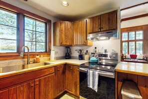 Une cuisine avec des armoires en bois, une cuisinière en acier inoxydable et une grande fenêtre.