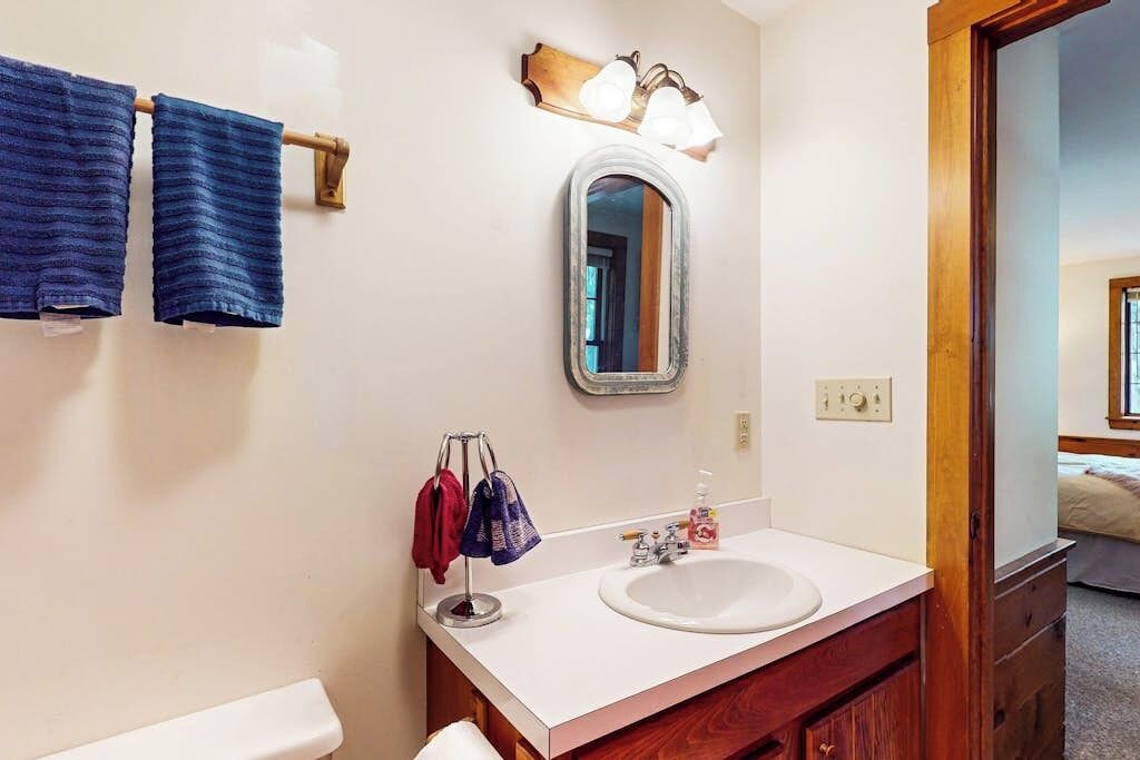 A bathroom with a white sink, a mirror, and two towels hanging on a towel rack.