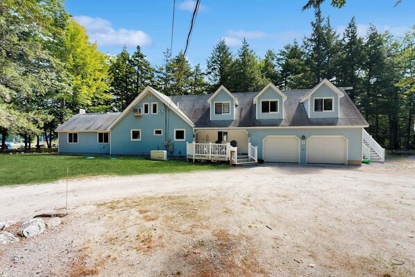 Une maison à deux étages avec un porche à l’avant, un garage et une allée.