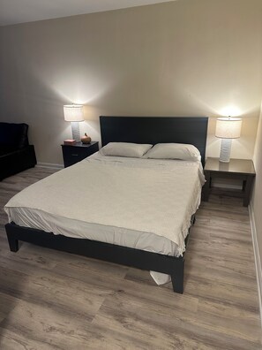 Ett sovrum med en säng, två sängbord, en lampa på varje bord och ett litet bord vid sängen med en lampa.