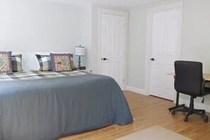 Een slaapkamer met een bed, een bureau en een stoel.
