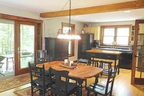 Een eetruimte met een houten tafel en stoelen, een kroonluchter en uitzicht op het buiten.