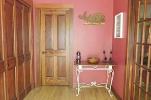A wooden door, a white metal table with a bowl and candles, and a welcome sign on a pink wall. - Spacious river home w/ pellet stove, outdoor dining area, fire pit, & BBQ grill (Litchfield)