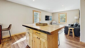 Une cuisine moderne avec des meubles en bois, un îlot central et un coin repas avec une chaise.