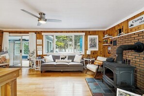 Ein gemütliches Wohnzimmer mit Kamin, einer Couch, einem Couchtisch und einem Schild mit der Aufschrift 'Camp in the Lake'.