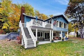 Ein zweistöckiges Haus mit Veranda, Treppe und einer Flagge.