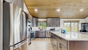 A modern kitchen with stainless steel appliances, wooden cabinets, and a large island. - Spacious mountain retreat with fire pit, hot tub, sauna, and foosball (Bethel)