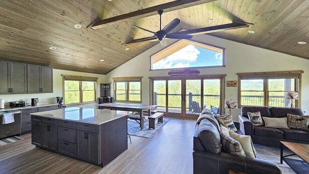 A spacious kitchen with a large island, a dining area, and a living room with a sofa and coffee table. - Spacious mountain retreat with fire pit, hot tub, sauna, and foosball (Bethel)