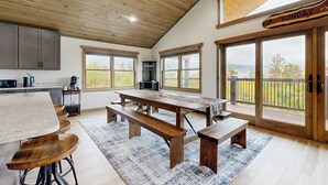 A spacious kitchen with a large island, wooden benches, and a dining table. - Spacious mountain retreat with fire pit, hot tub, sauna, and foosball (Bethel)