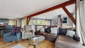 A spacious living area with a sofa, armchairs, a coffee table, and a kitchen in the background. - Spacious Mountain Chalet with Sauna, Deck, and Ski/Snowboard Adventures Nearby (Bethel)