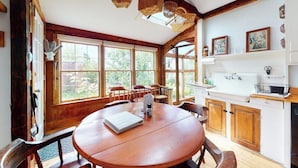 A wooden dining table with chairs, a white kitchen with wooden cabinets, and large windows. - Historic home with porch & mountain/valley views - great for weddings (Paris)