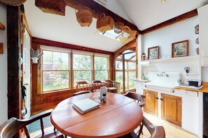 A wooden dining table with chairs, a white kitchen with wooden cabinets, and large windows. - Historic home with porch & mountain/valley views - great for weddings (Paris)