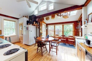 A kitchen with wooden floors, a round table, and chairs, a stove, and a ceiling fan. - Historic home with porch & mountain/valley views - great for weddings (Paris)