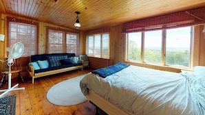 A wooden cabin room with a bed, a sofa, and large windows. - Historic home with porch & mountain/valley views - great for weddings (Paris)