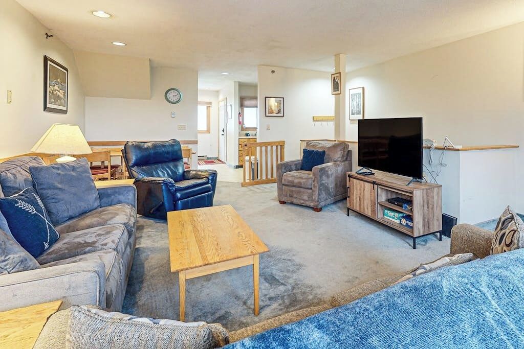 A living room with a sofa, armchairs, a coffee table, a TV, and a wooden cabinet.